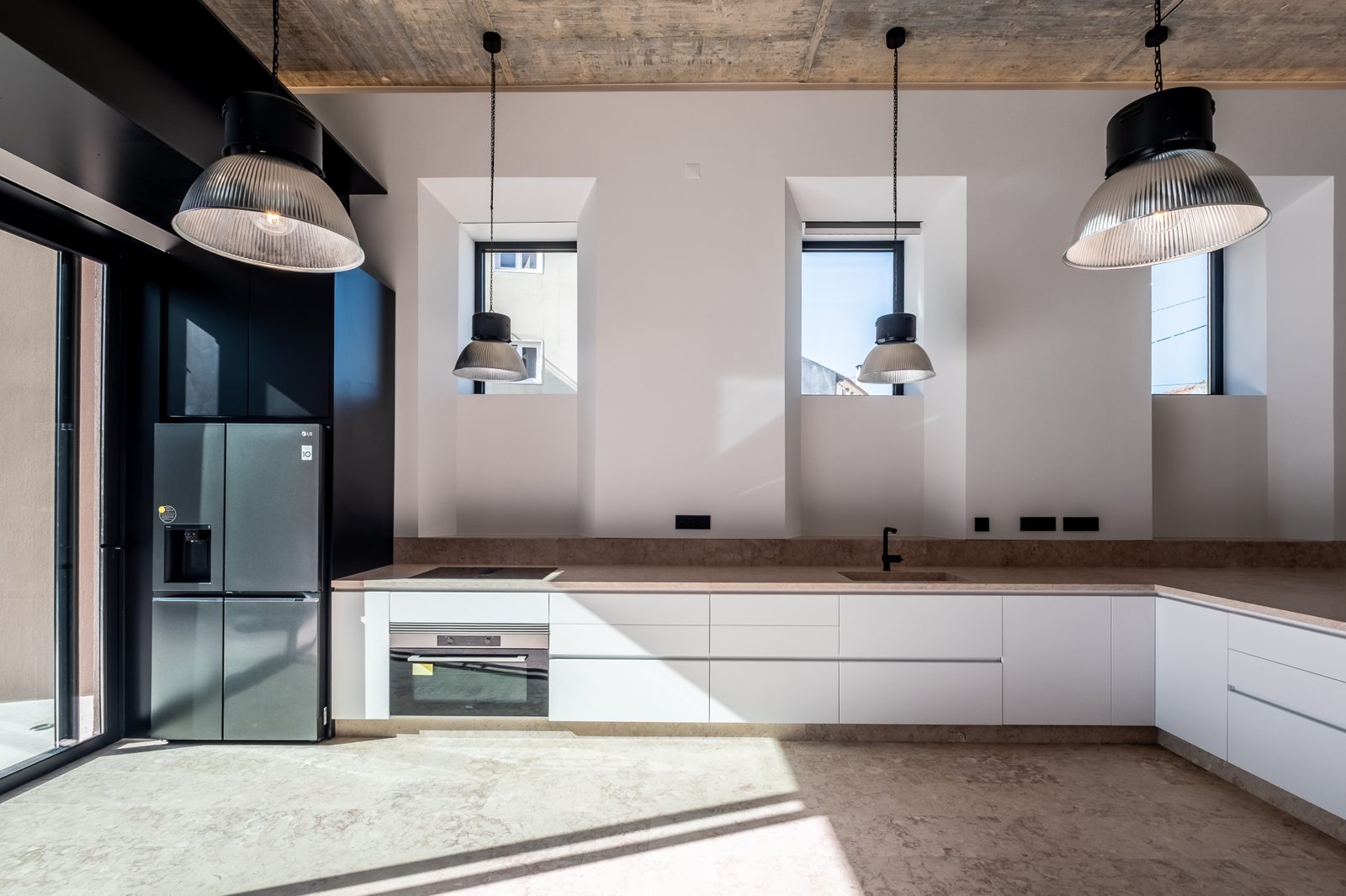Cozinha da Casa do Bairro com os vãos abertos na parede original de pedra