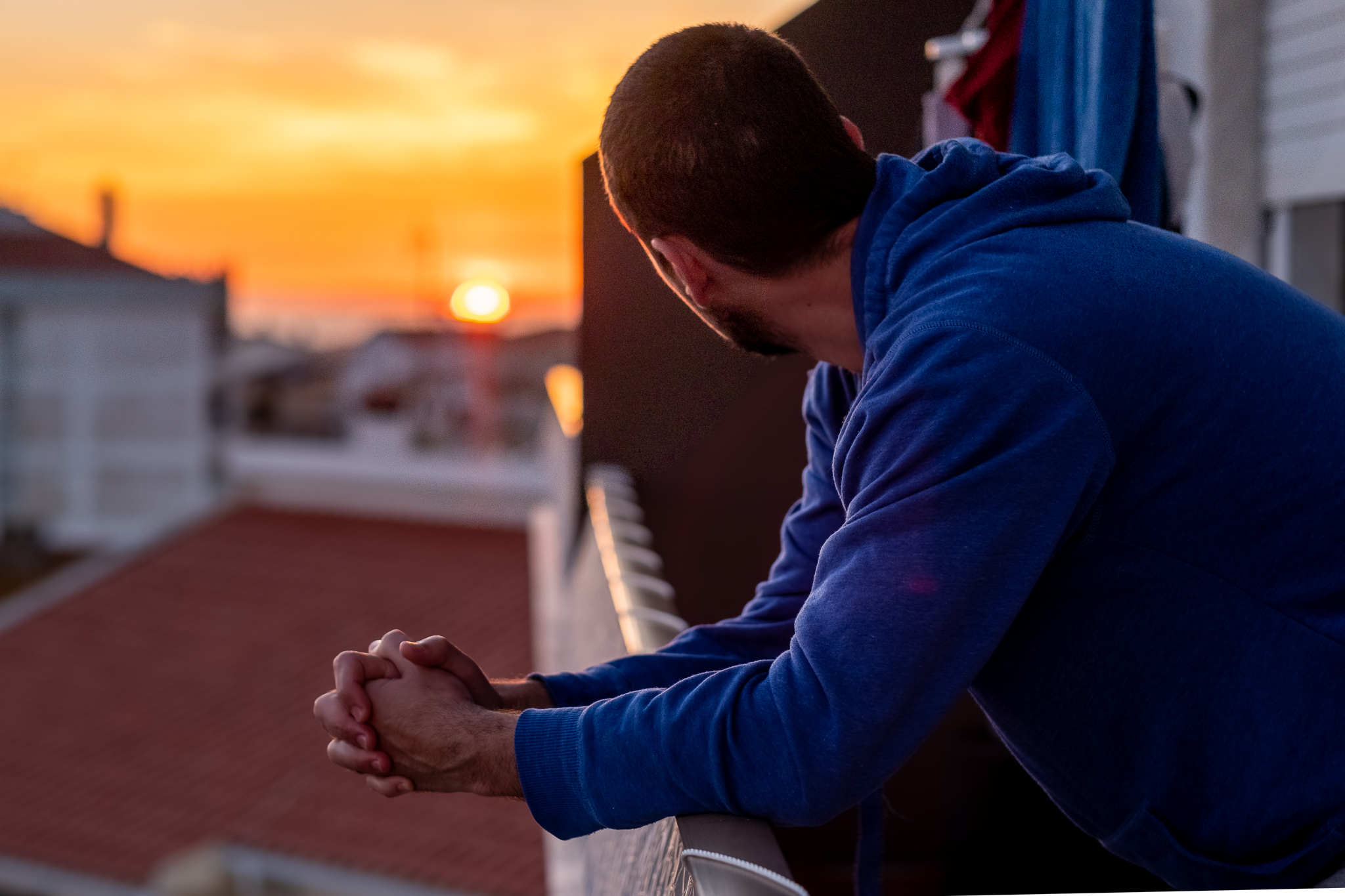 Homem num terraço a contemplar o pôr do sol — a emoção de encontrar a casa certa