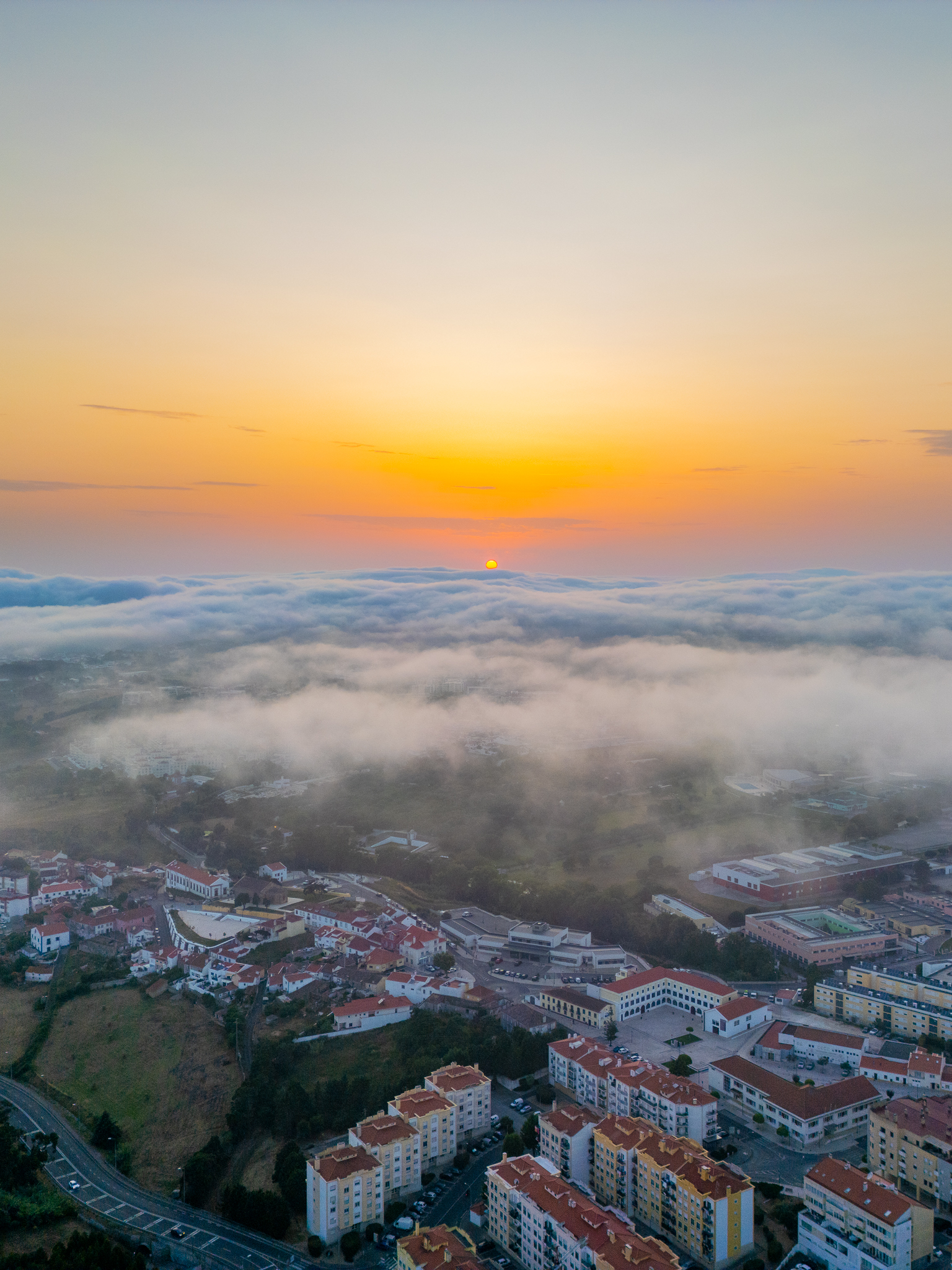 Vista aérea de Mafra ao entardecer com mar de nuvens