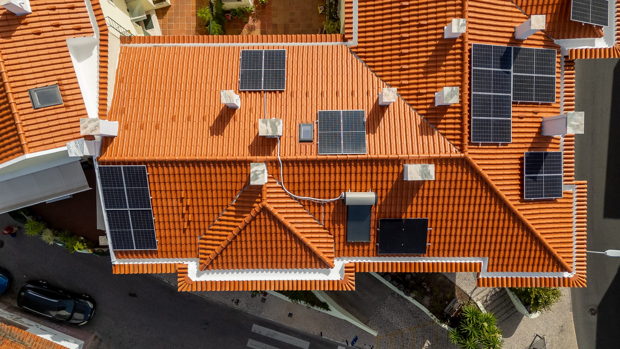 Vista aérea da cobertura em telha cerâmica com os painéis solares e o depósito do coletor térmico