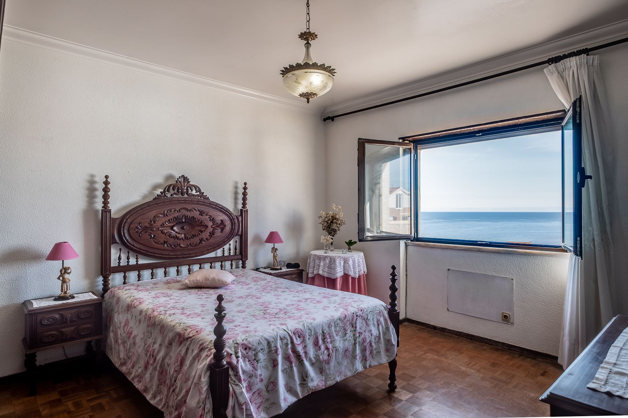 Suíte com soalho em madeira, cama de época e vista mar