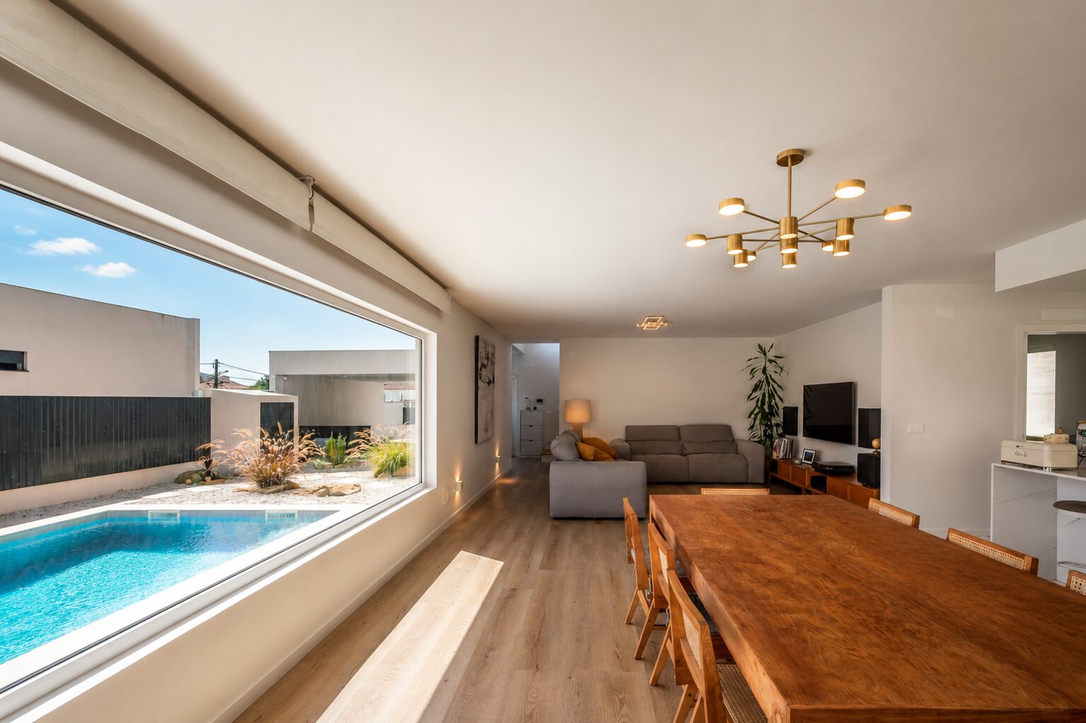 Sala de estar e jantar num vão contínuo, com janela panorâmica sobre a piscina