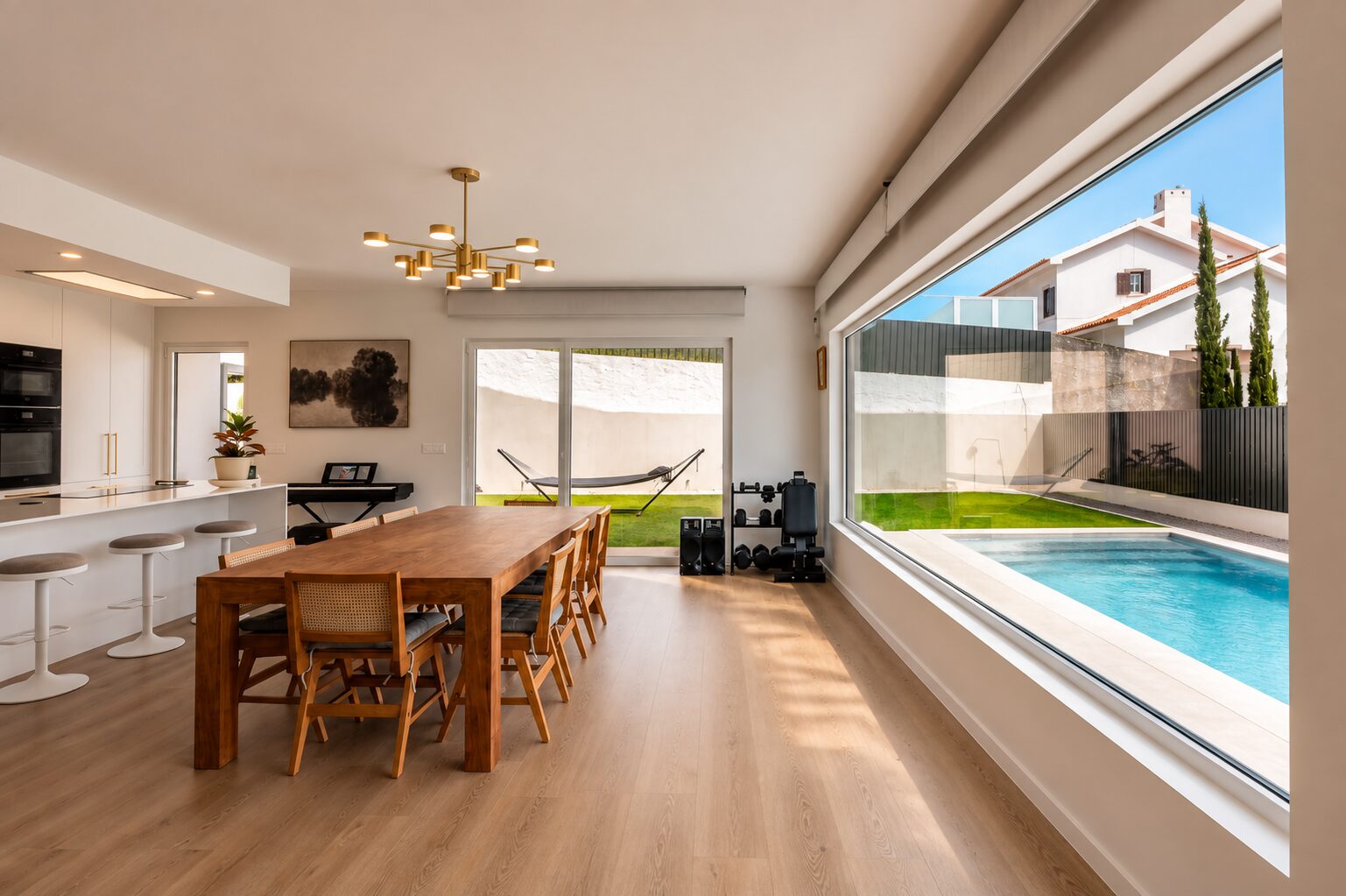 Sala de jantar com mesa e janela panorâmica sobre a piscina