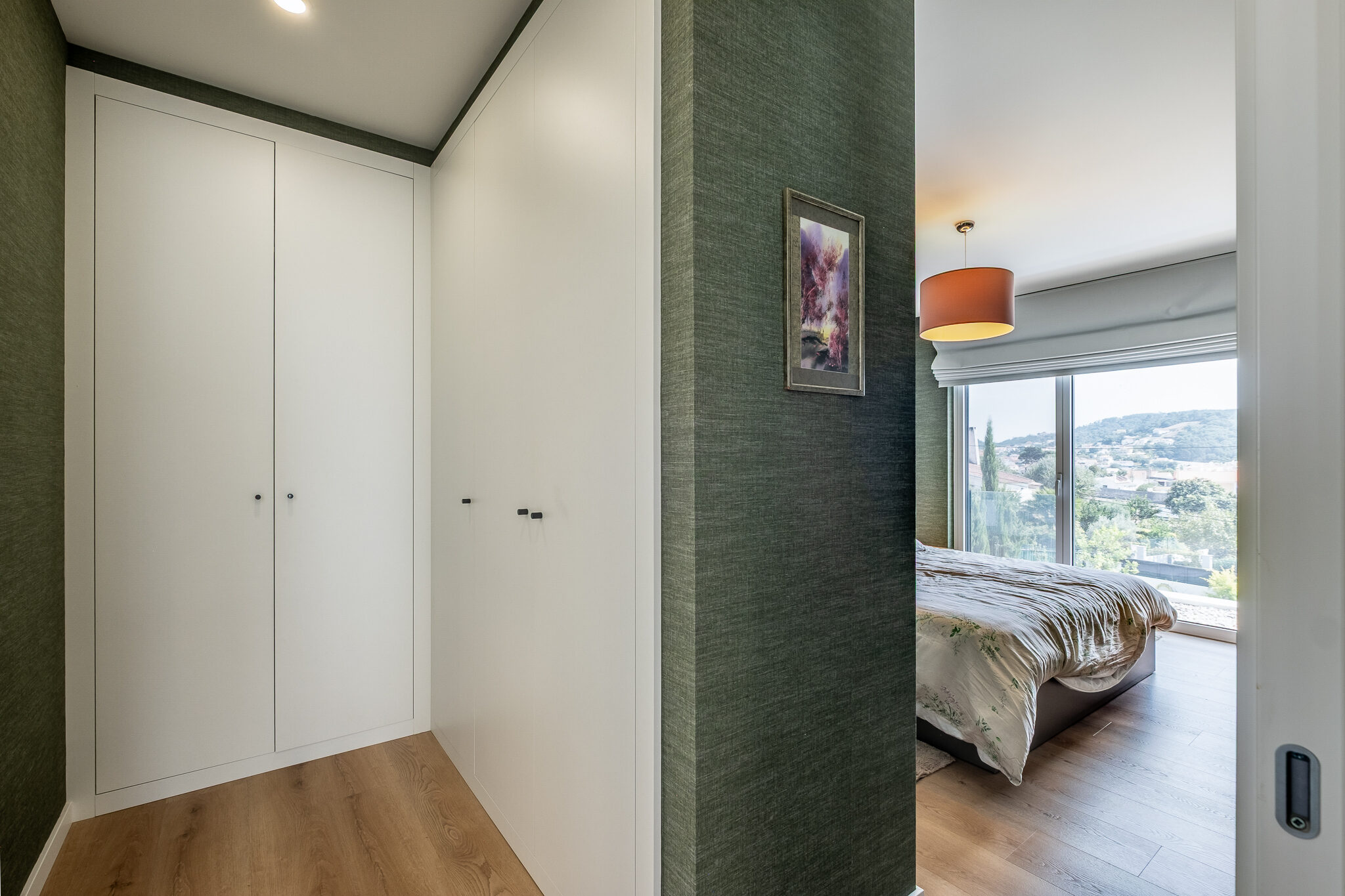 Closet da suíte com roupeiros brancos embutidos e acesso ao quarto
