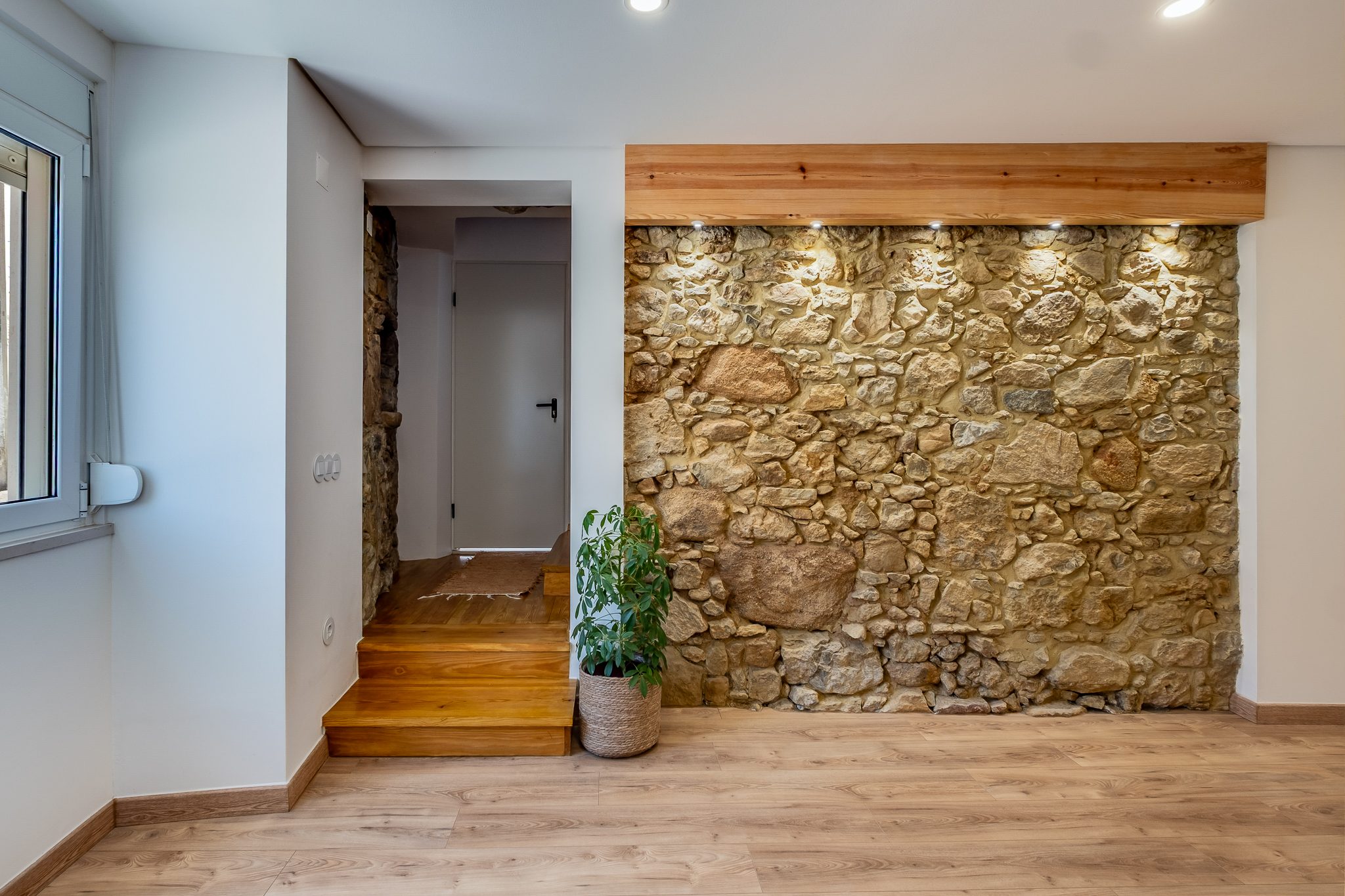 Sala com parede em pedra natural original, na moradia T3 reconstruída em Vila Franca do Rosário, Mafra