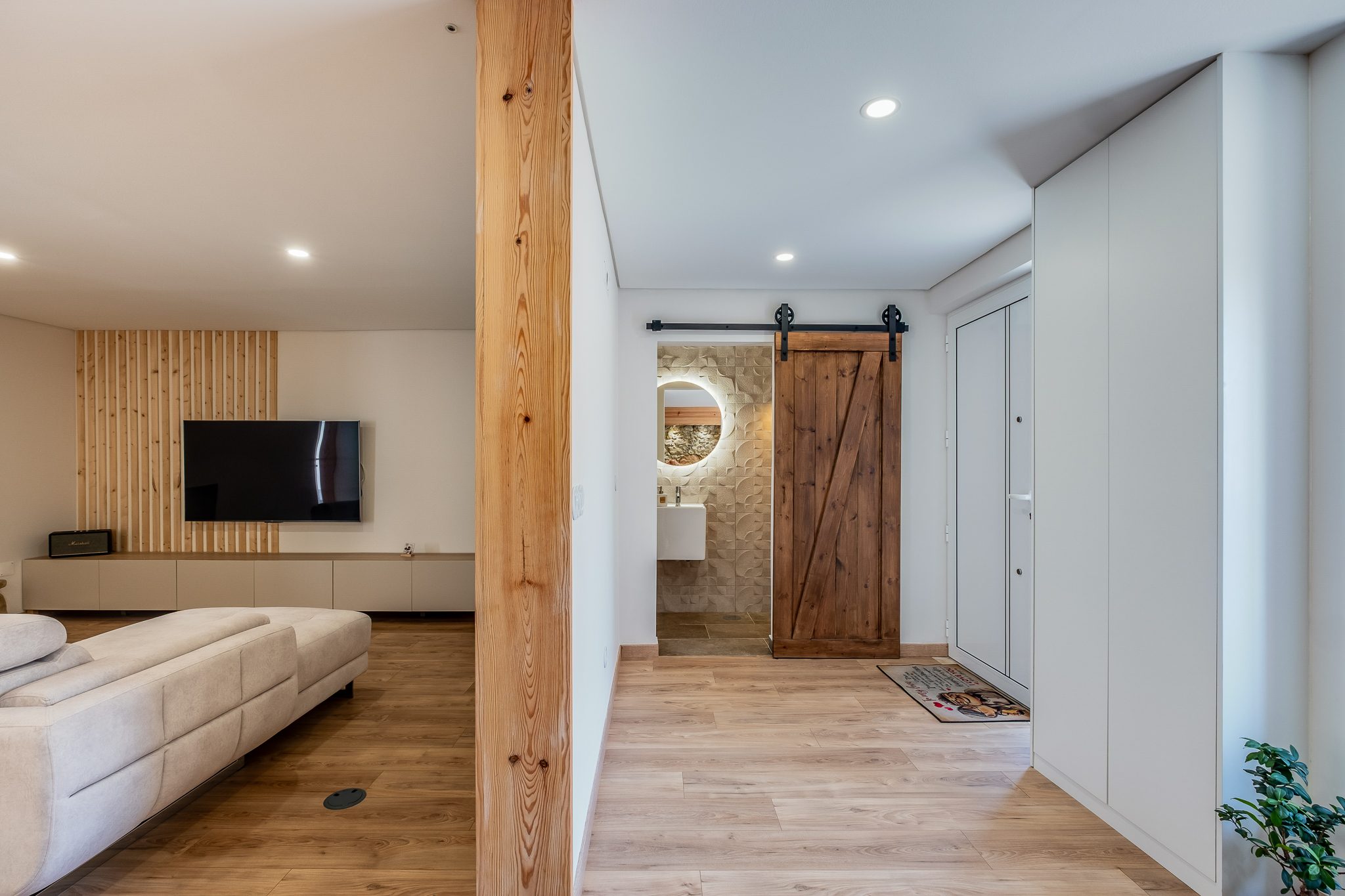 Sala aberta para o hall de entrada, com porta de celeiro em madeira maciça