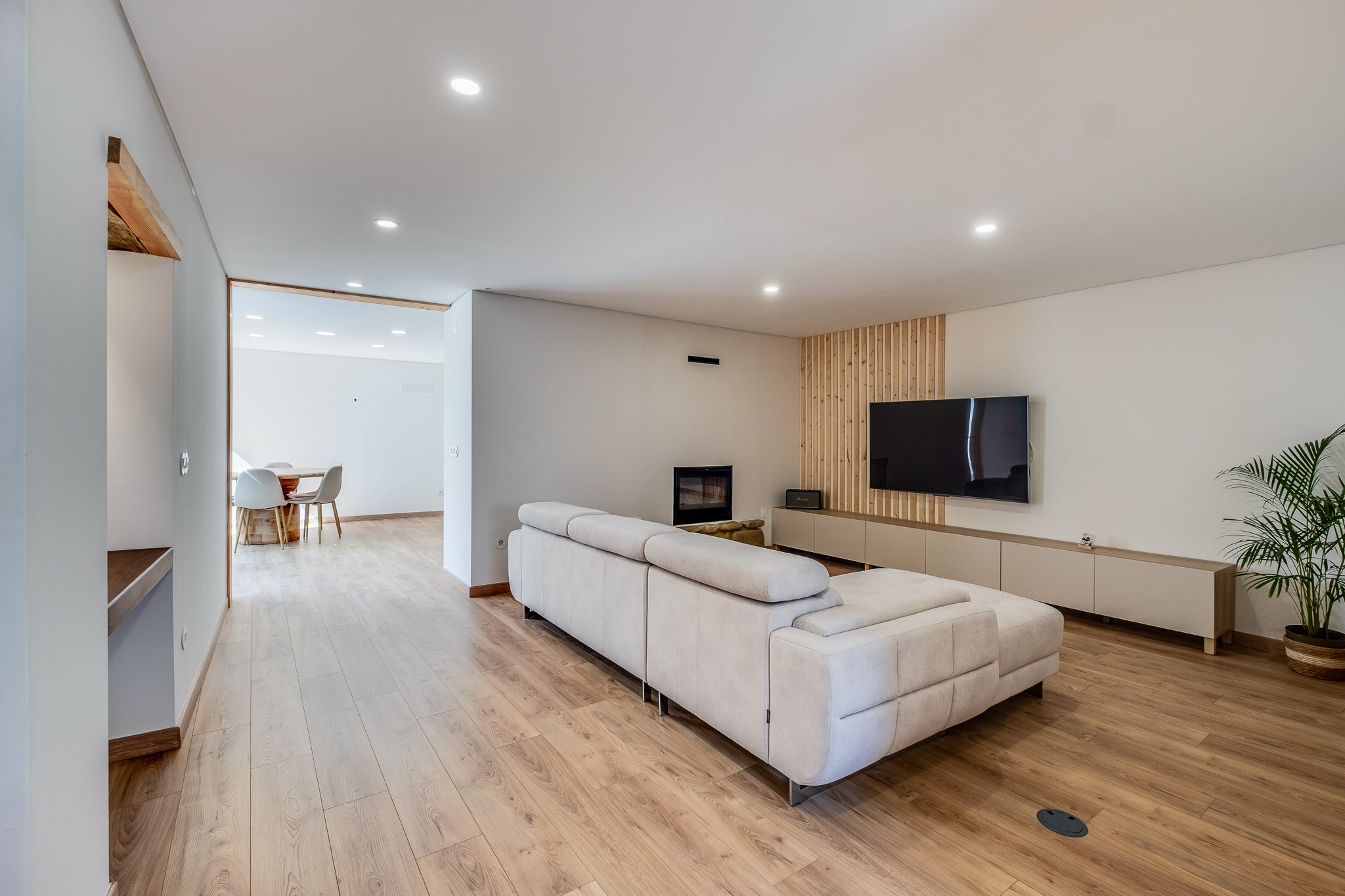 Sala de estar ampla com lareira e painel ripado em madeira
