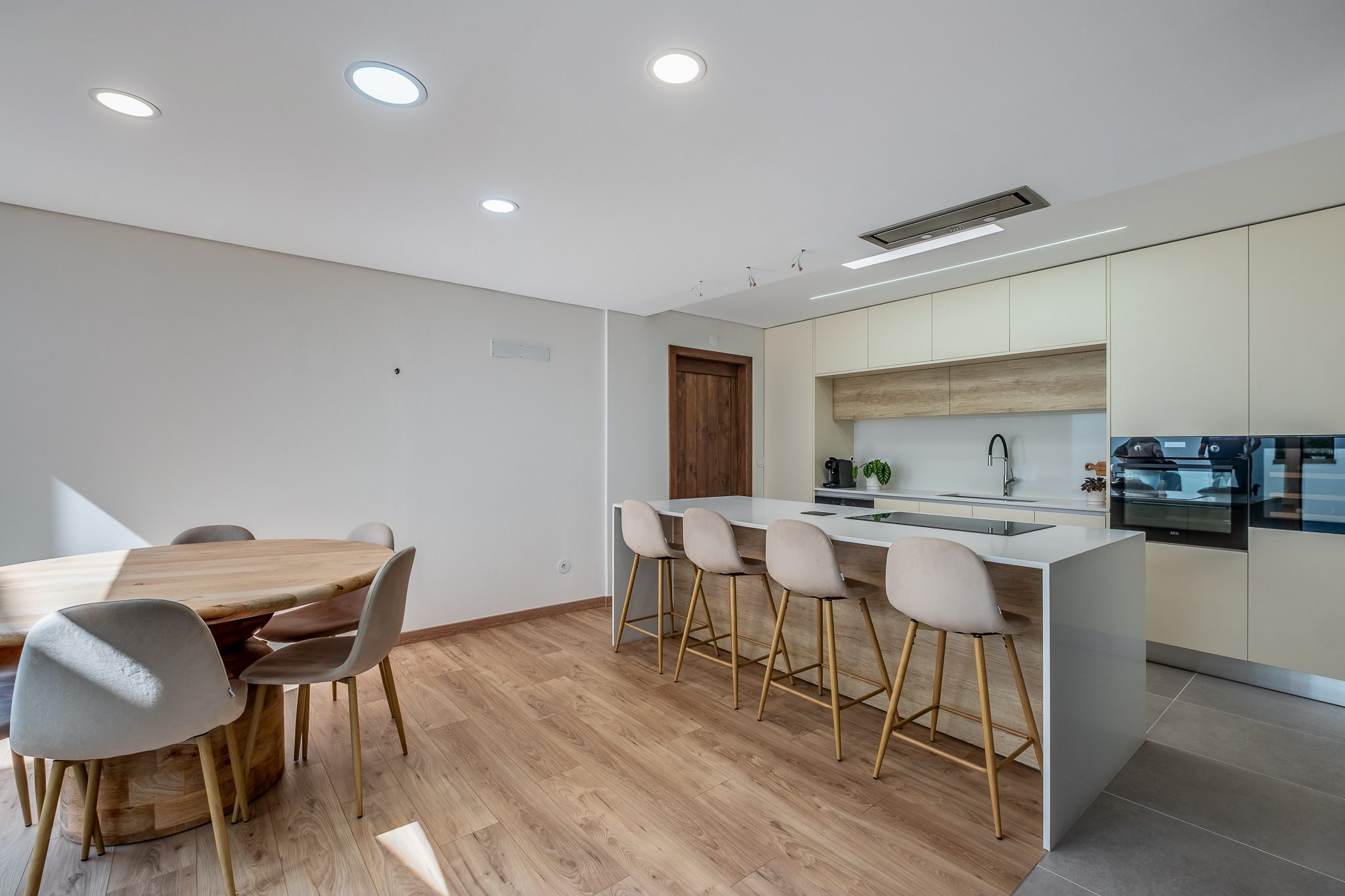 Cozinha equipada com ilha, placa de indução e mesa de jantar em madeira maciça