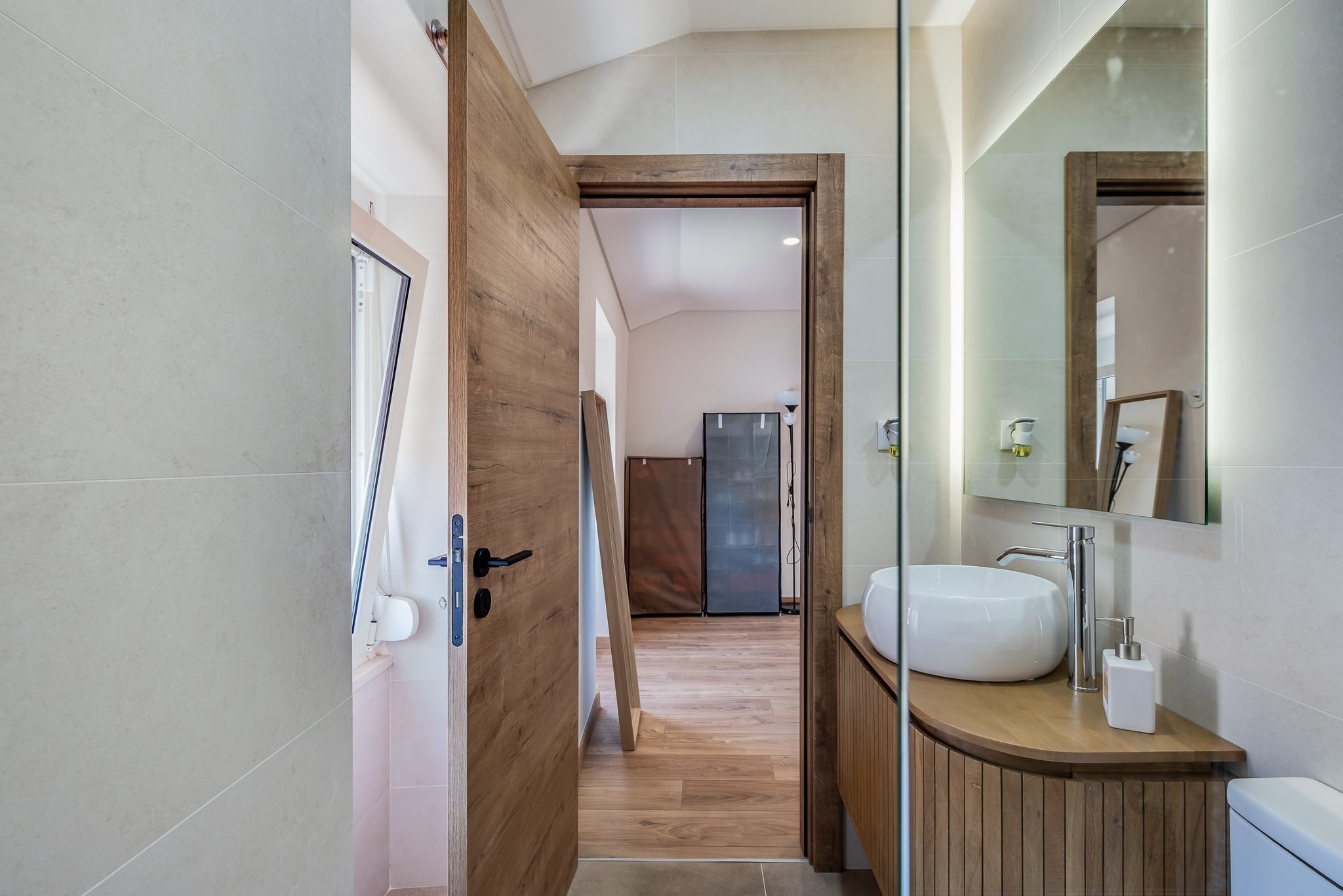 Casa de banho da suite com móvel ripado em madeira e base de duche