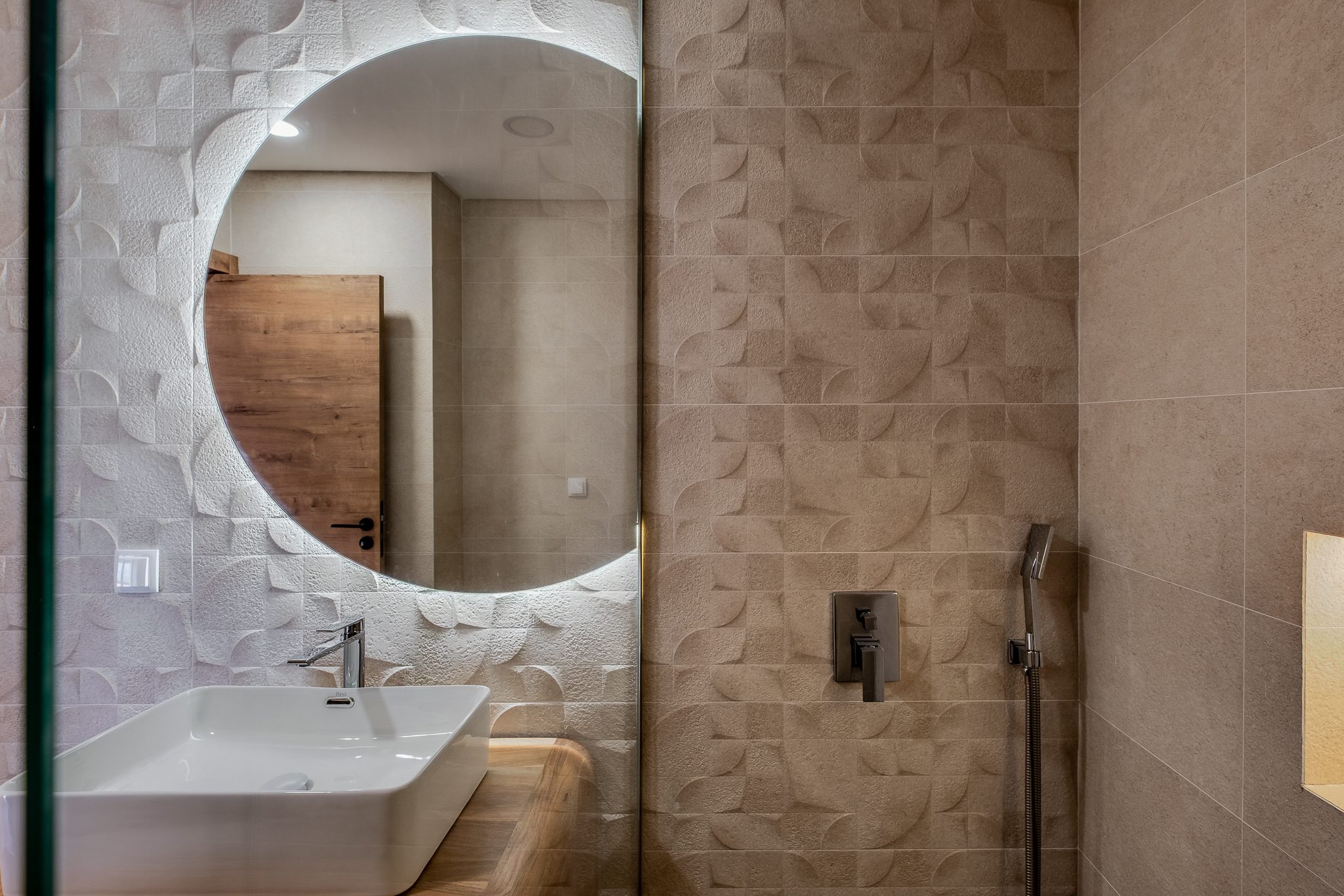 Casa de banho revestida a azulejo de relevo com espelho circular retroiluminado