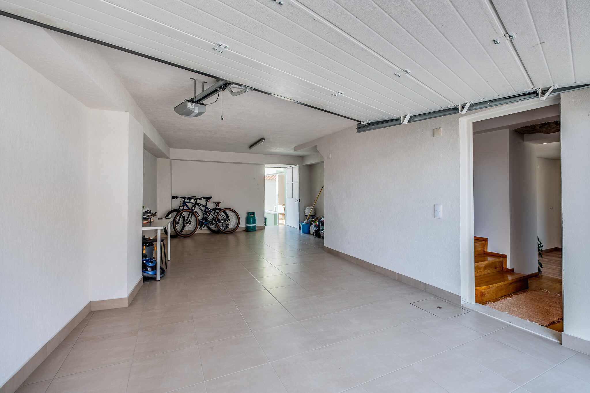 Garagem fechada com portão automático, espaço para duas viaturas e acesso interior à casa
